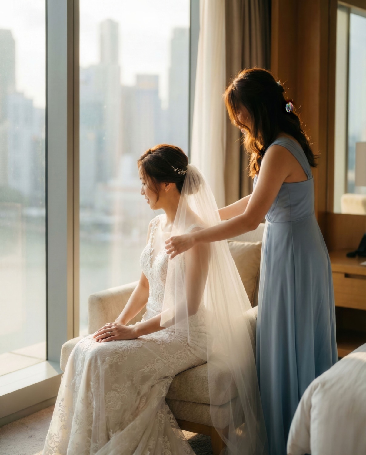 Bride getting ready with her bridesmaid by the window